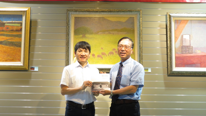 本校藝術中心主任何修仁(左)接受廖本義老師贈送畫冊